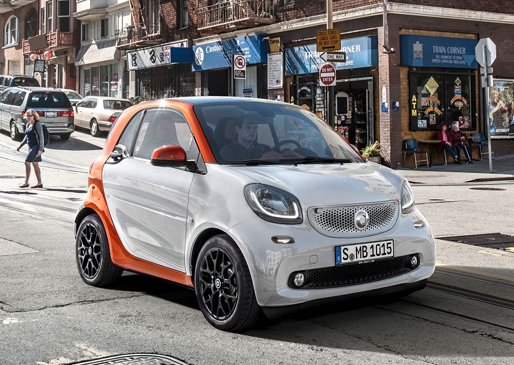 Chico conduciendo Smart ForTwo de color blanco con la parte trasera y los espejos de color naranja