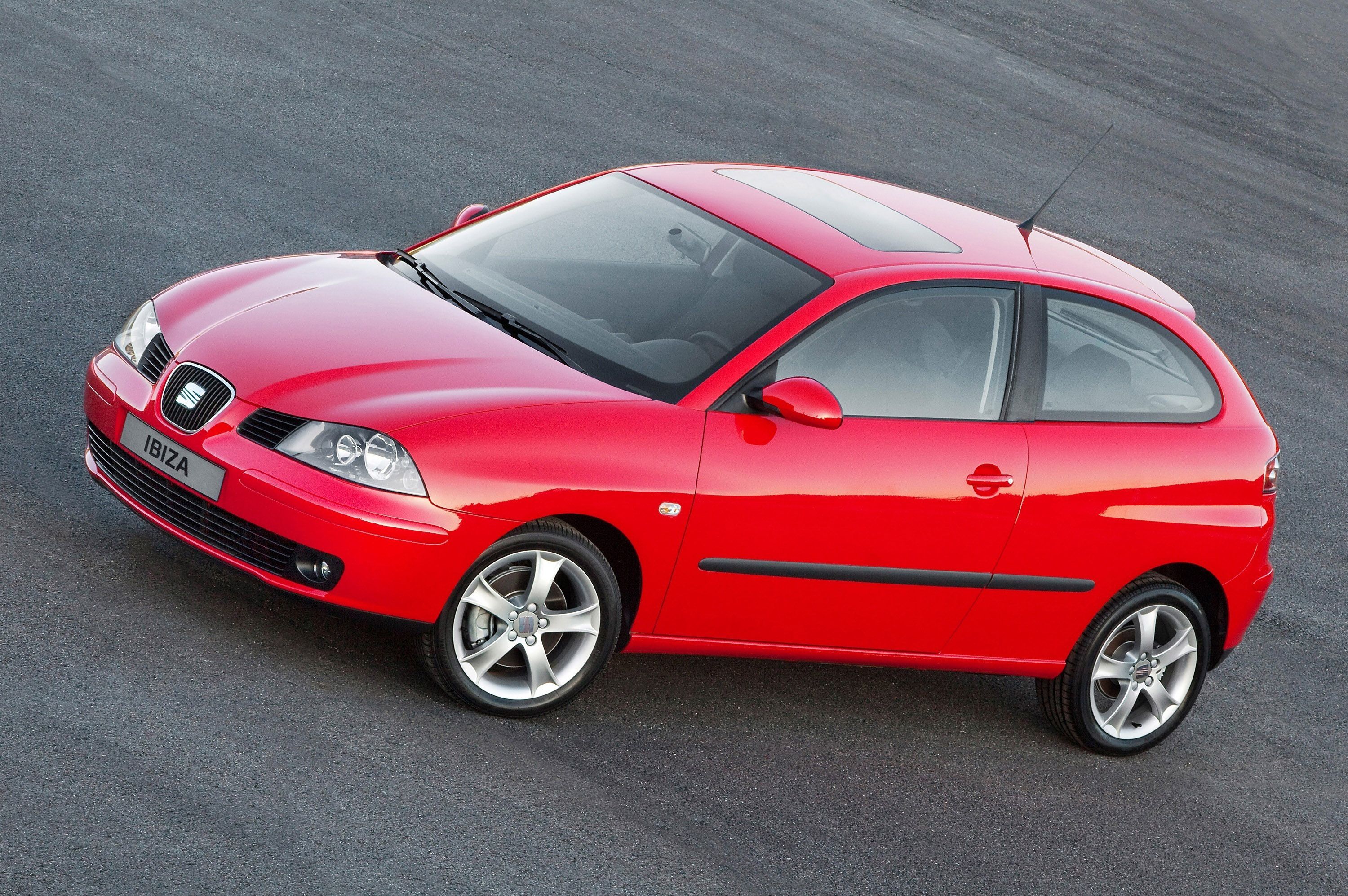 Perspectiva frontolateral aérea del Seat Ibiza antiguo de color rojo con techo solar