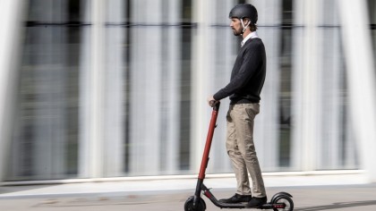 Persona montando un patinete eléctrico con casco y de una forma segura