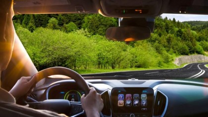 Conductor practicando la conducción ecológica por una carretera que atraviesa un verde bosque